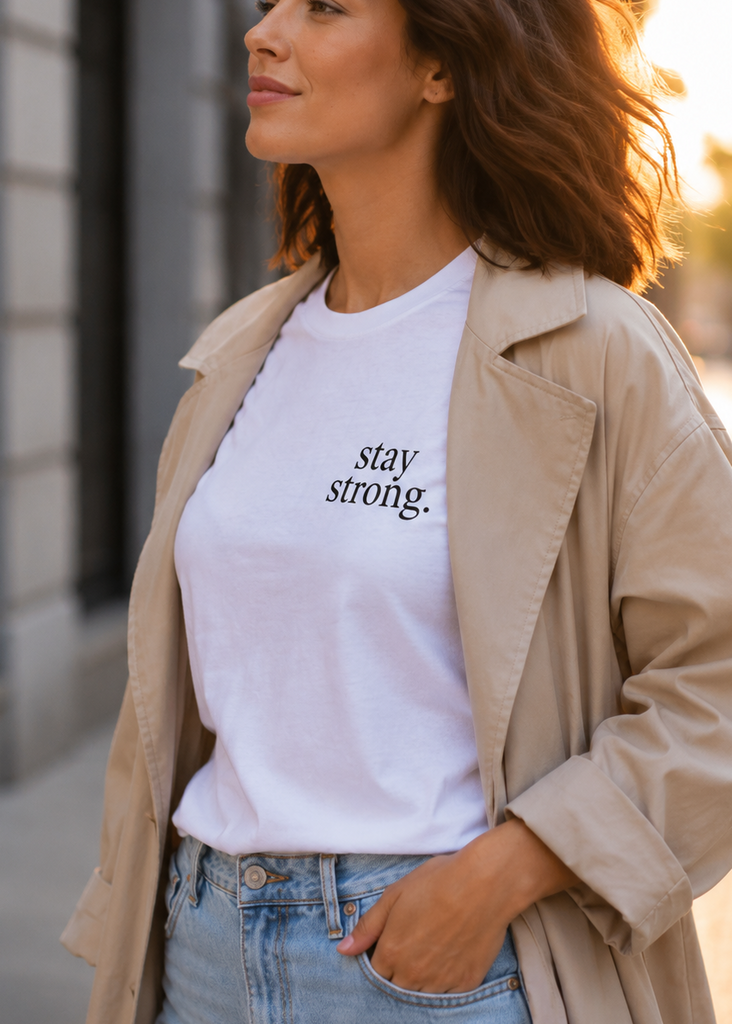 Woman wearing a white t-shirt with 'stay strong.' text on a city street.