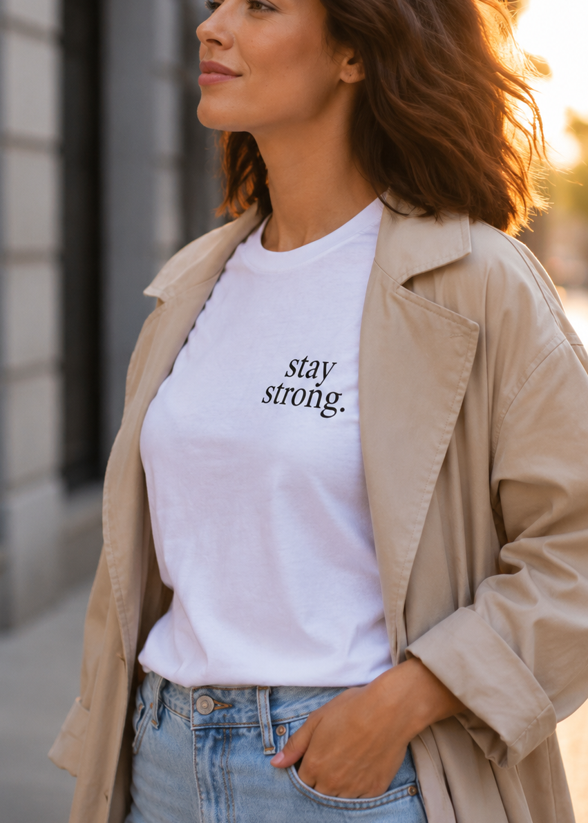 Woman wearing a white t-shirt with 'stay strong.' text on a city street.